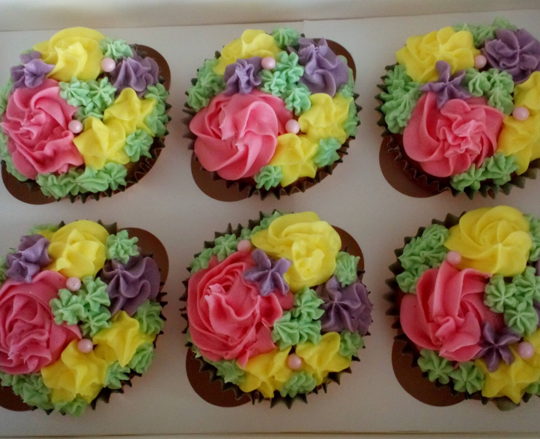 Box of floral coloured cupcakes
