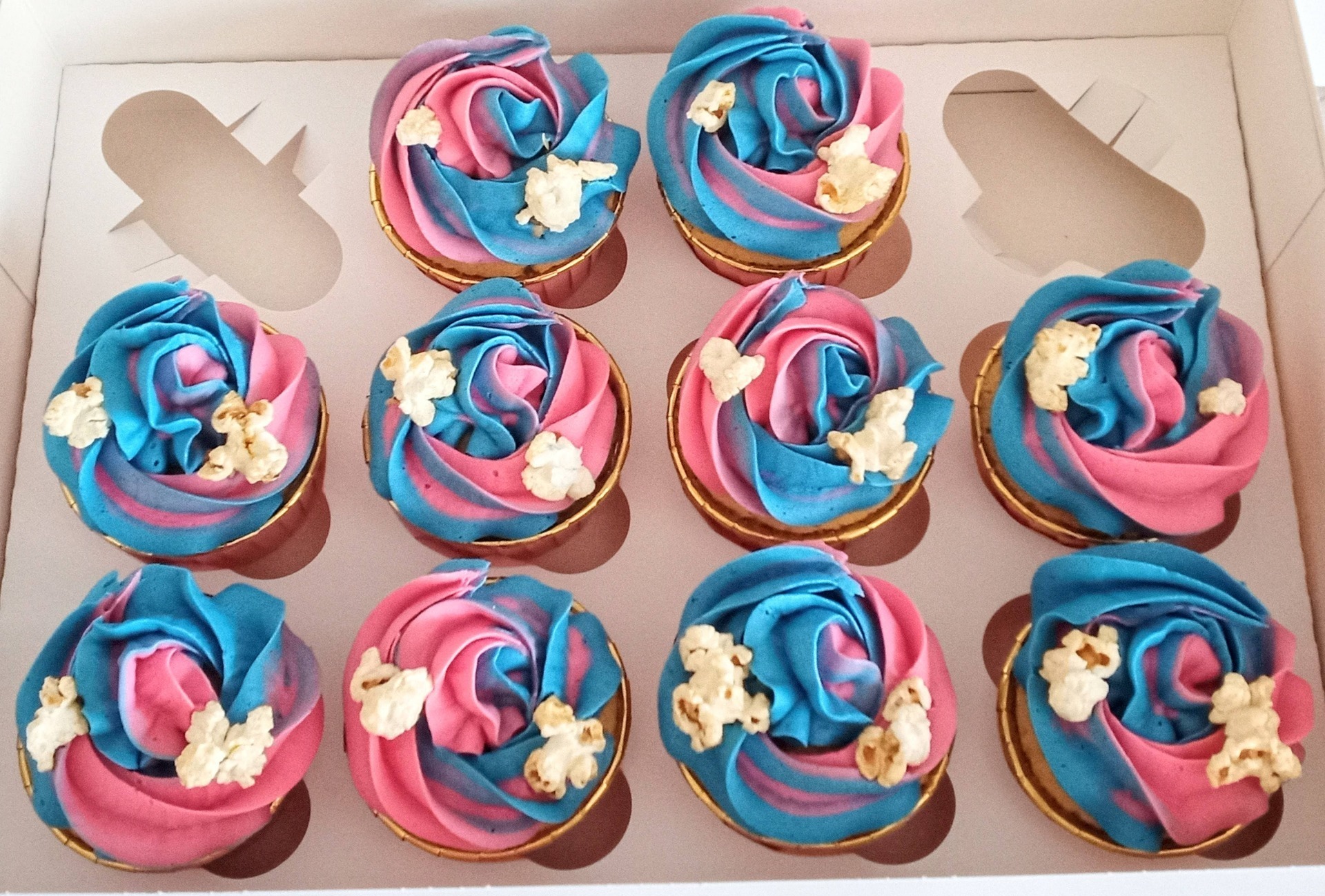 fun birthday cupcakes with blue and pink swirl topped with popcorn